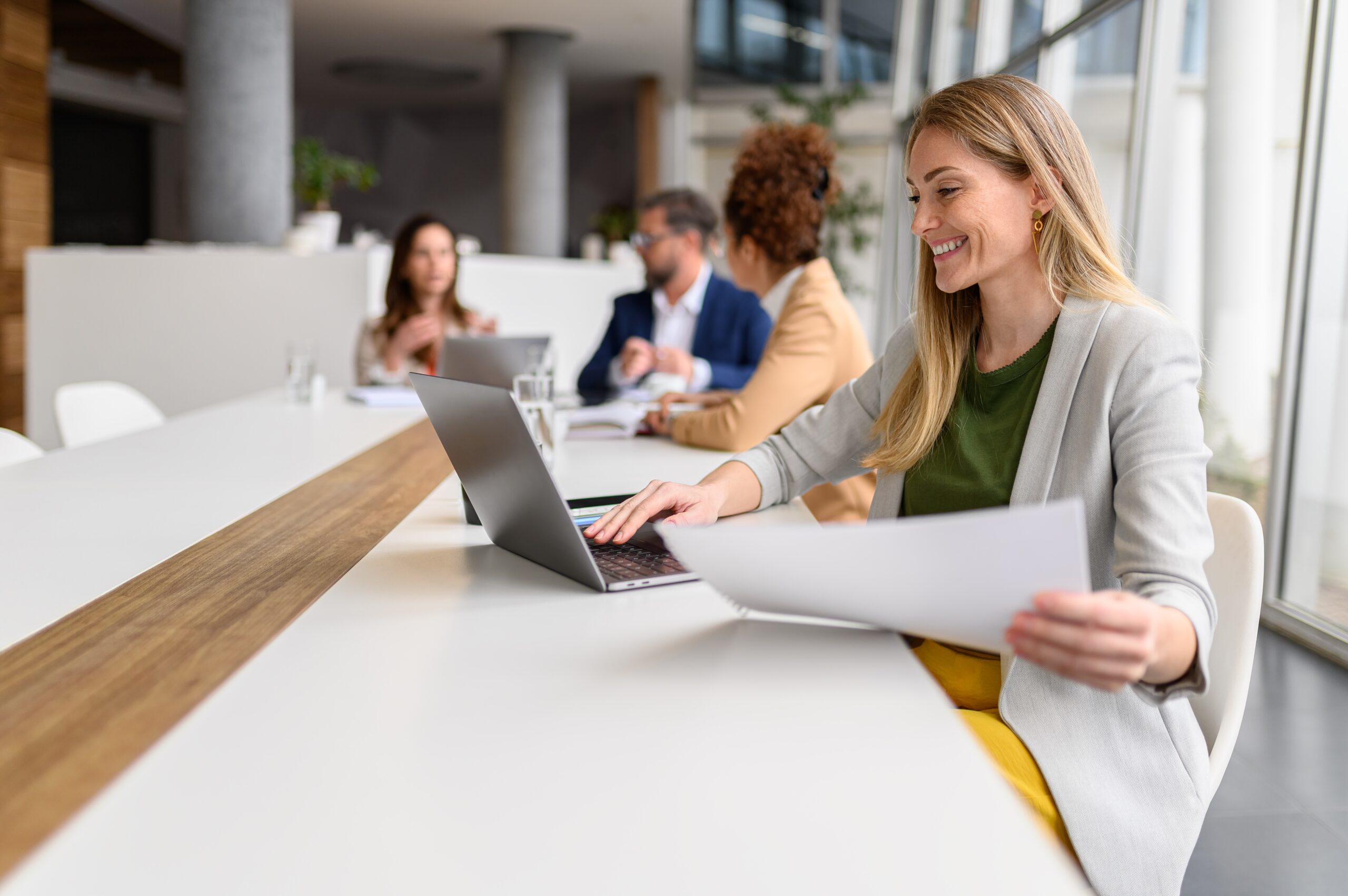 Confident,Businesswoman,Smiling,And,Examining,Financial,Report,Over,Laptop,While